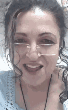 a woman wearing glasses and a blue shirt smiles