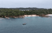 an aerial view of a boat in the ocean near a small island
