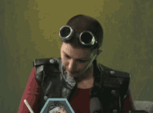 a man wearing goggles and a leather vest looks at a picture