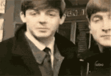 two men in suits and ties are standing next to each other in a black and white photo .