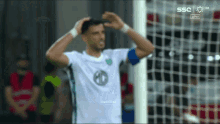 a soccer player stands in front of a net with ssc written on the bottom right