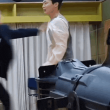 a man in a white shirt is standing in a room with a laptop on his back