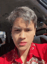 a man in a red shirt is sitting in a car