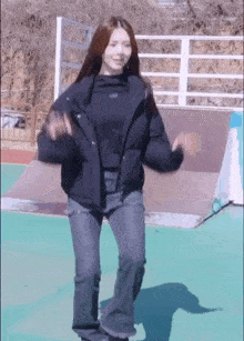 a woman in a black jacket is standing on a skateboard ramp .