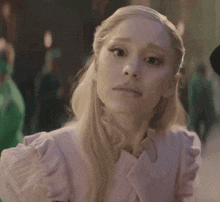 a woman with blonde hair is wearing a pink jacket and ruffled sleeves
