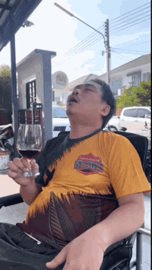 a man wearing a shirt that says ' snoop dogg ' on it holds a glass of wine