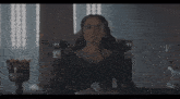 a woman in a black dress is sitting in a throne with her eyes closed