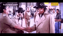 a man in a trench coat and cowboy hat is shaking hands with another man .