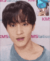 a close up of a person 's face in front of a kms sign