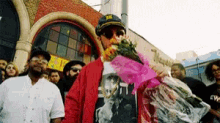 a man holding a bouquet of flowers in front of a crowd of people