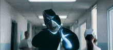 a man in a mask is walking down a hospital hallway with a nurse behind him .