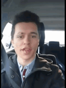 a man in a suit and tie is sitting in a car