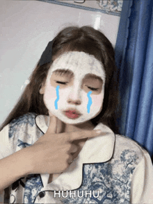 a girl with a white mask on her face is pointing at her face