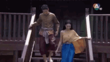 a man and a woman are walking down a set of stairs holding hands .