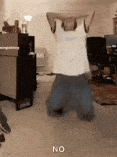 a man is kneeling down in a room with his arms in the air and the word no on the floor .