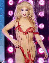 a drag queen is standing in front of a curtain with pink lights