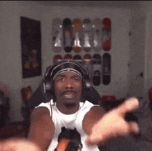 a man wearing headphones and a headband is sitting in a room with skateboards on the wall .