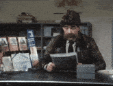 a man sitting at a desk looking at a magazine that says ' ziekte en wef '