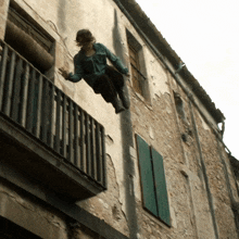 a woman is sitting on a balcony on the side of an old building