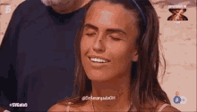 a woman is smiling in front of a sign that says ' x factor ' on it