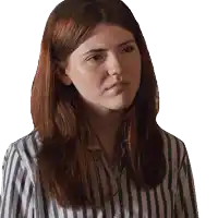 a woman with red hair and a striped shirt looks at the camera