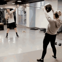 a man and a woman are doing exercises in a gym with dumbbells on the floor