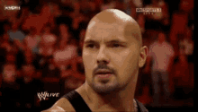a bald man with a beard is standing in front of a crowd watching a w live show