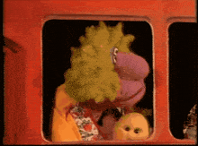 a cartoon character with a green and purple head looks out a window