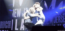 a group of people hugging on a stage in front of a sign that says " new jersey "