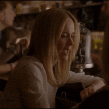 a woman in a white shirt is drinking a glass of wine
