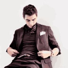 a man in a suit and striped shirt adjusts his belt