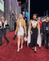two women are walking on a red carpet in front of a sign that says " elt "