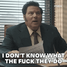 a man in a suit and tie is sitting at a desk and says i don 't know what the fuck they do