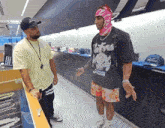 a man wearing a native boy shirt talks to another man in a store