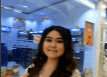 a woman in a white shirt is smiling in front of a store window