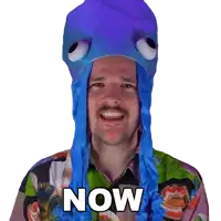 a man wearing a purple octopus hat and a colorful shirt says now