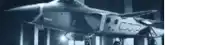a fighter jet is parked in front of a building in a dark room .