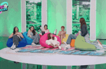 a group of women are sitting on bean bag chairs in a room with a sign that says sbs