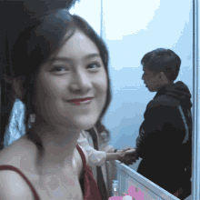 a woman in a red dress is smiling while a man in a black hoodie is shaking her hand
