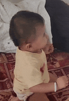 a baby in a yellow shirt is sitting on a couch .