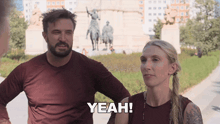 a man and a woman are standing in front of a statue and the woman says yeah