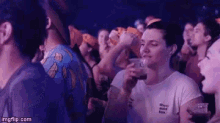 a woman is holding a cup of beer in a crowd of people at a concert .