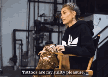 a woman in a black adidas sweatshirt sits in a directors chair