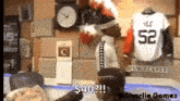 a man is standing in front of a clock and a jersey that says yee 52 on it .