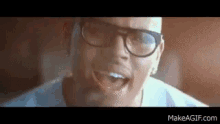 a man wearing glasses and a white shirt is singing into a microphone .
