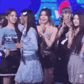 a group of young women are standing next to each other on a stage and applauding .