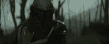 a close up of a man in a helmet holding a gun in a forest .