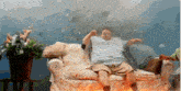 a man is sitting on a couch with his arms outstretched in front of a fire