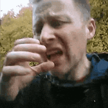 a man in a blue jacket is eating something with his hands .