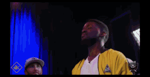 a man in a yellow jacket stands in front of a sign that says tna